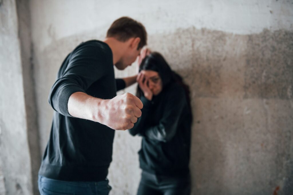 Man balt vuist tegenover vrouw die zich beschermt, symbool voor escalatie bij agressie